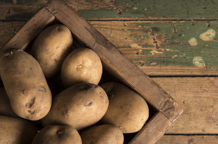 흙이 묻는 감자가 나무상자에 담겨 있는 사진