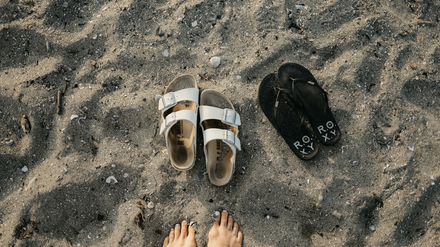 해변에 버켄스탁 과 록시 샌들이 나란히 놓여있는 사진