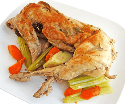 네모난 하얀 접시에 연갈색으로 잘 구워진 토끼고기 전체요리가 있고 옆에는 볶은 당근과 야채가 있다.