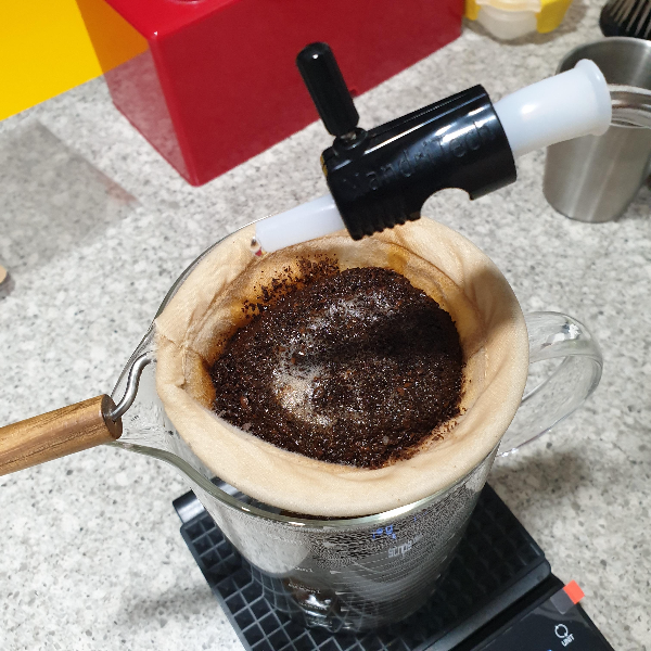 물줄기 조절 밸브를 장착한 드립포트로 융 필터에 물을 부어하고 있다. 융필터에는 커피 파우더가 들어있다.