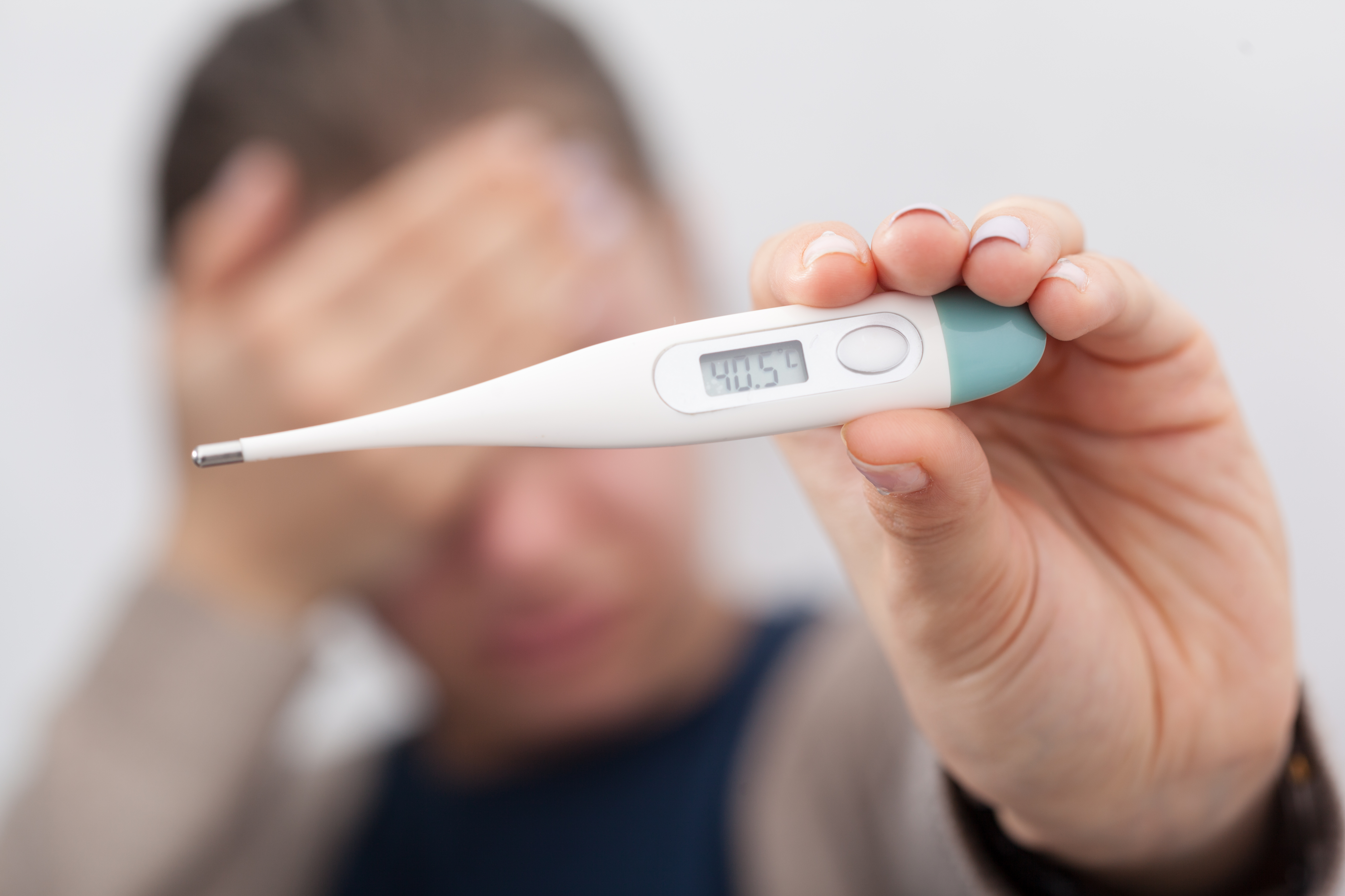 열이 많이 나서 머리가 많이 아픈 환자가, 전자체온계로 체온을 잰 후에 체온이 40.5도가 나온 것을 보여주며 찍은 사진