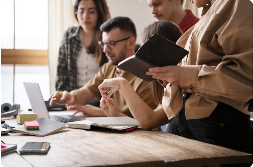 여러 명의 사람들이 노트북에 있는 내용을 다같이 보고 있는 모습
