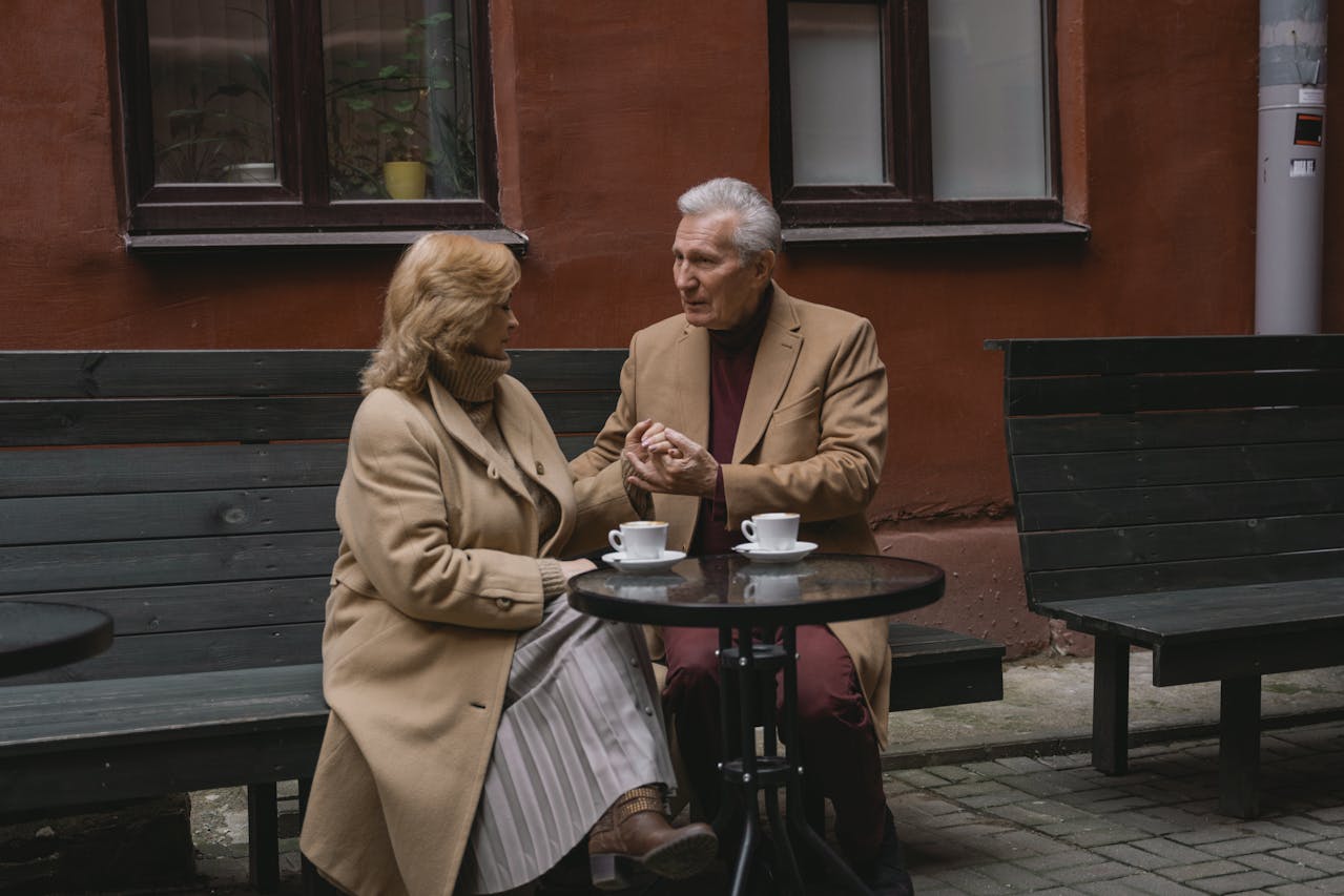 카페 야외 테이블에서 대화를 나누는 시니어 부부의 모습 - 은퇴 후 안정적인 생활을 상징하는 장면