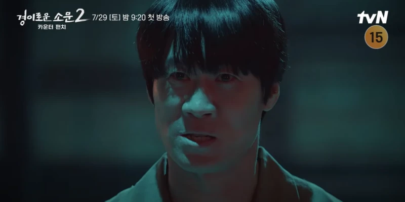 어느 어두운 실내를 배경으로 험한 인상을 짖고 있는 경이로운 소문 2의 마주석을 연기하는 배우 진선규