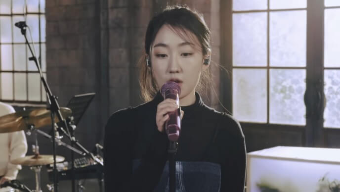 허회경이-검은-옷을-입고-마이크를-손에-쥔채-노래를-부르고-있는-사진