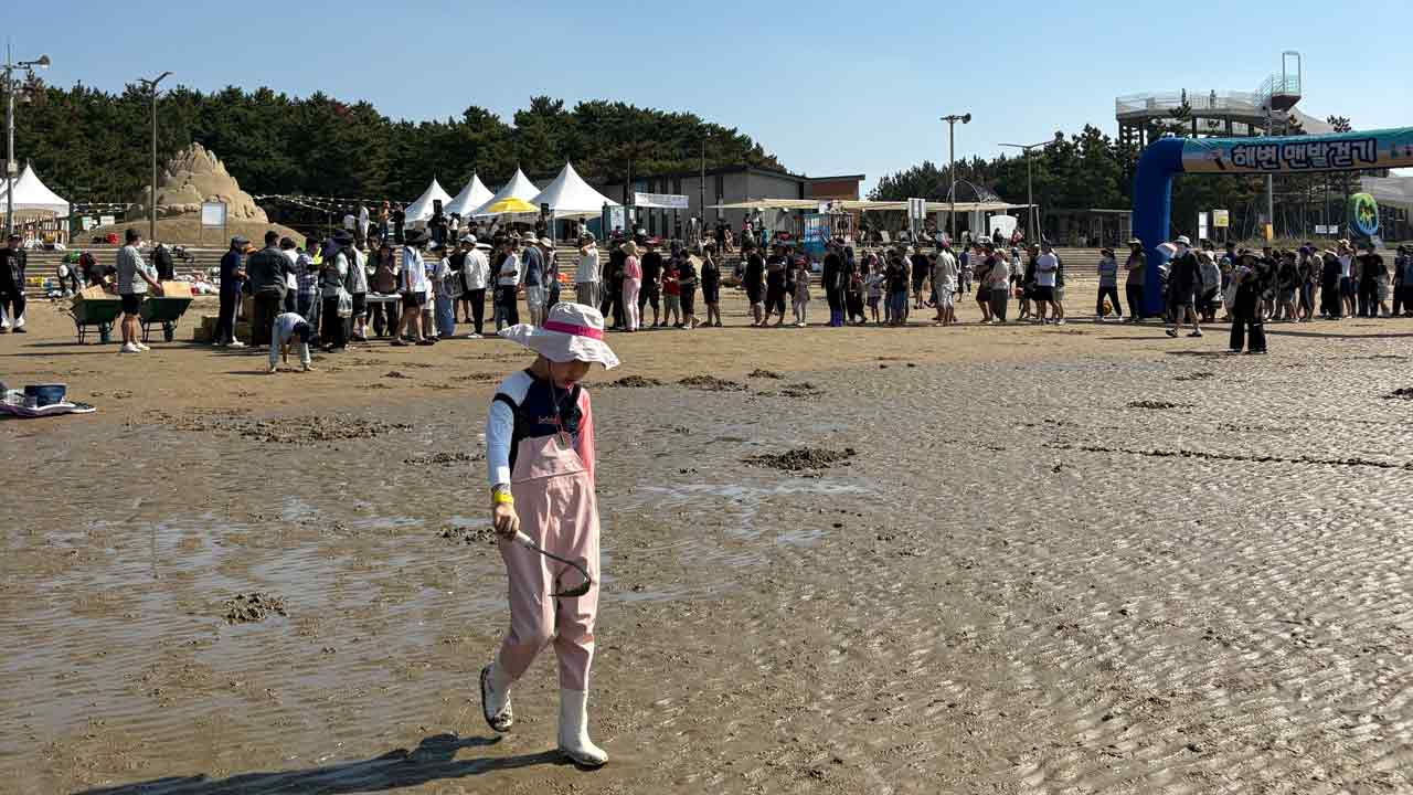아이가 호미를 대여 받고 해변을 걷고 있는 모습
