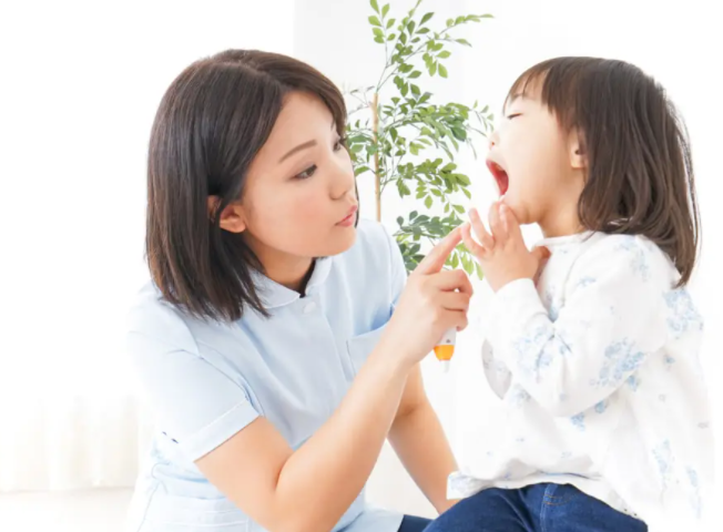 입안을 검사하는 간호사와 여자아이