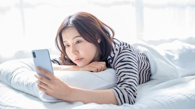 어두운 침실에서 밤늦게 스마트폰 숏폼을 시청하는 모습 이미지