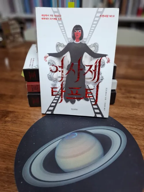 신비로운 보랏빛 우주 성운 이미지와 나란히 배치된 여사제 타프티 책 표지 (The book cover of Tufti the Priestess placed alongside a mystical purple cosmic nebula image)