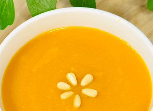 흰그릇에 노란 호박죽이 담겨있고, 호박죽 위에는 잣 5개가 꽃모양으로 올려져 있는 사진