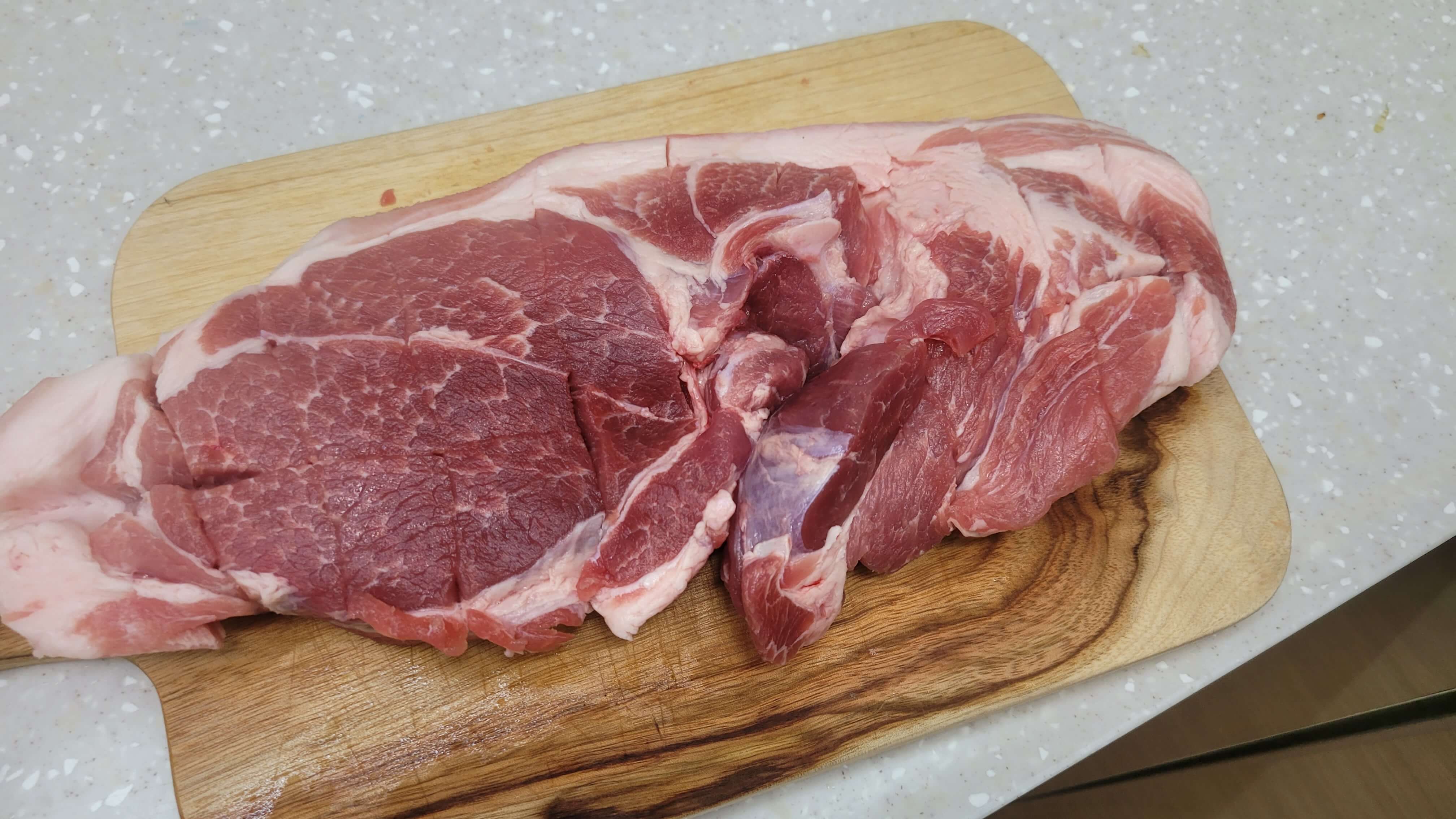 요리 도마 위 신선한 수육용 돼지 고기, 칼집이 내어져 있다.