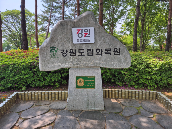 푸른 나무를 배경으로 한 강원도립화목원 바위 표지석