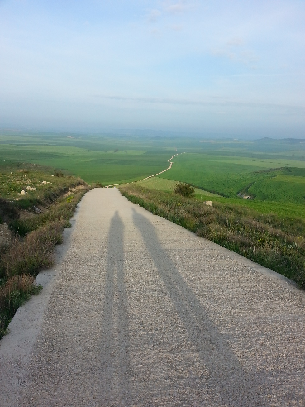 길 양쪽에는 푸른 밀밭이 펼쳐져 있고&#44; 길위에는 두 사람의 그림자가 길게 늘여져 있음