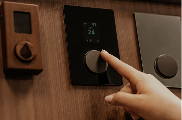 스마트 온도 조절기를 낮추는 손, 가정 내 에너지 절약 모습