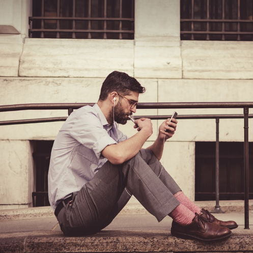 이어폰을 끼고 스마트폰을 보며 생각에 잠긴 남성의 길거리 모습