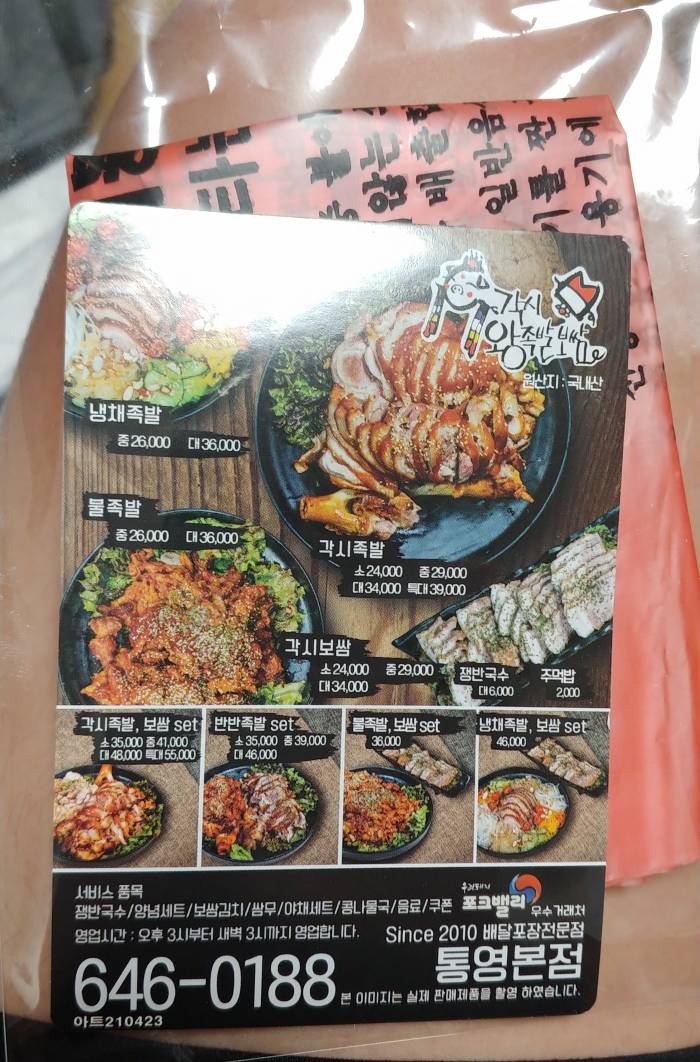 족발-메뉴가-적혀있는-종이뒤에-주황색-쓰레기봉투가-있다