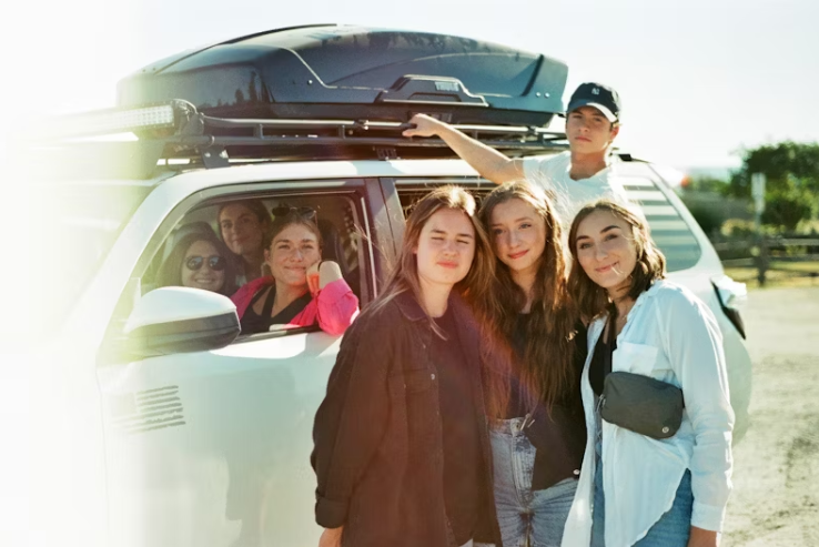 여러 명의 가족이 SUV 차량 앞에 함께 서서 웃고 있는 모습