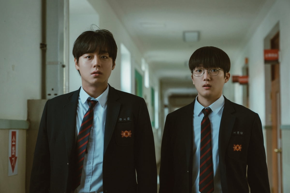 약한영웅 class2의 주인공 연시은과 서준대가 나란히 교복을 입고 교실복도에서 놀란 모습으로 카메라를 응시하고 있는 이미지