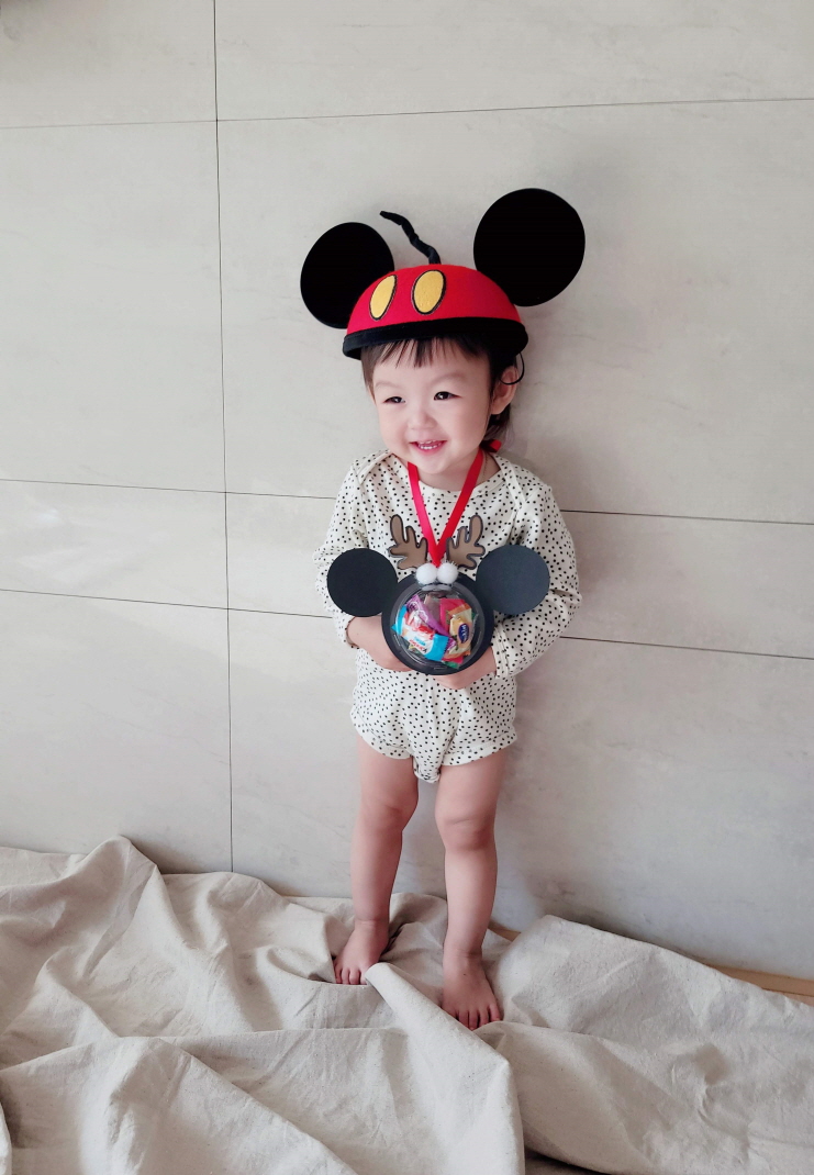 미니마우스 모자에 미니마우스 모양의 간식목걸이를 걸고 포즈를 취하는 아기모델