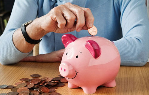 핑크색 돼지 저금통에 동전을 넣고 있는 여성