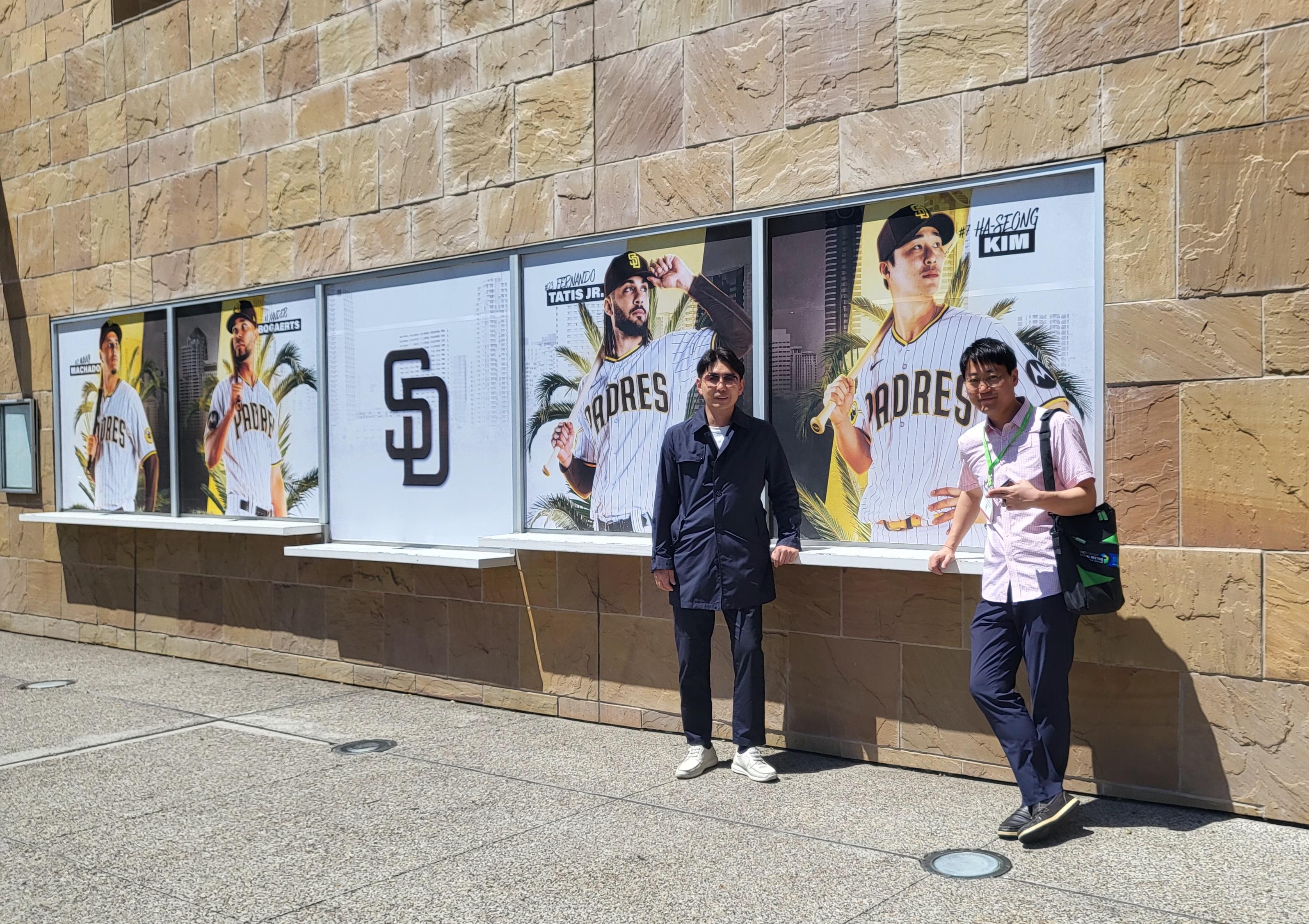 김하성 선수 포스터 앞에서 사진 찍은 두 명의 남성