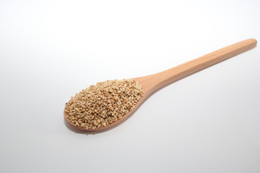 야생에서 채취를 한 참깨를 깨끗하게 세척한 후에 하얀 바닥 위에 나무숟가락에 참깨를 가득 담은 것을 놓아두고 찍은 사진