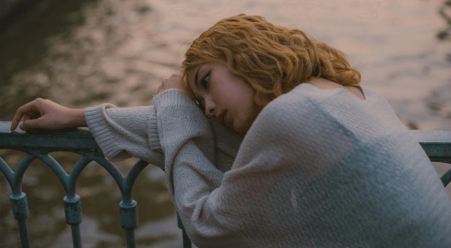 우울한 여자가 난간에 기대여 있다