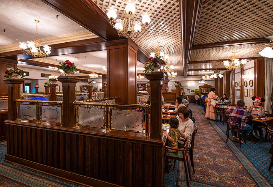 중세시대의 분위기로 장식이 되어 있는 식당. 전반적으로 넓고 테이블과 의자에 사람들이 앉아서 식사를 하고 있다.