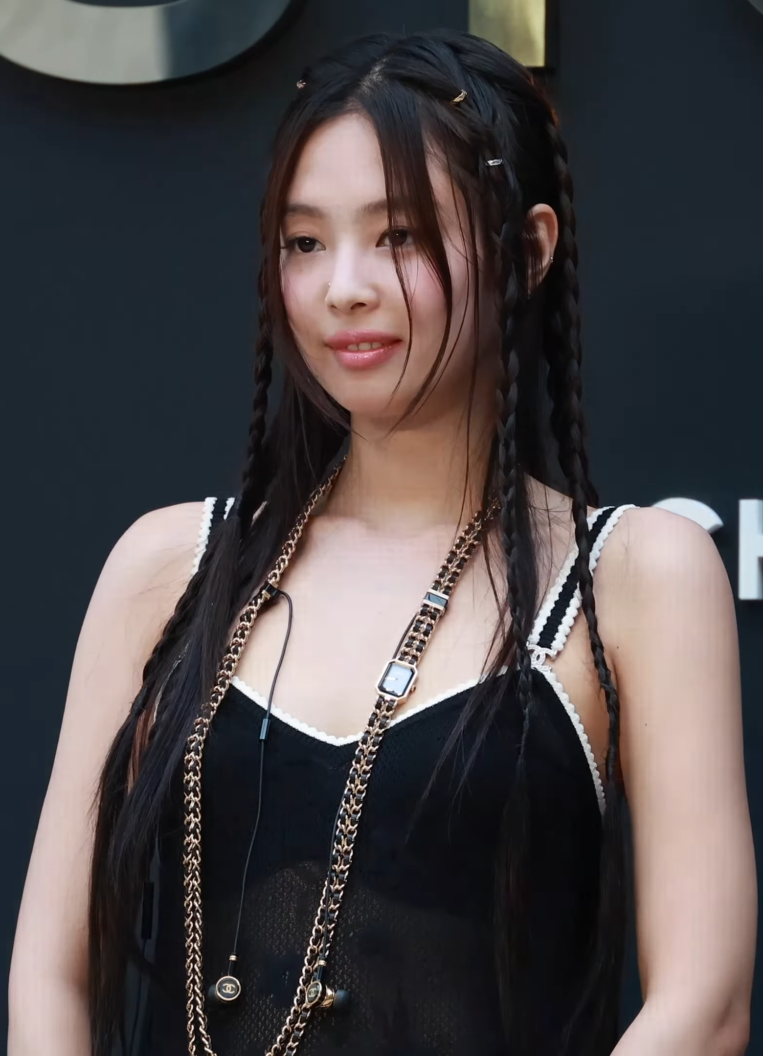 Jennie smiling at the July 2024 Chanel Coco Crush event in a black top with white trim.