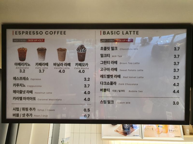 카운터 상단에 정갈하게 배치된 카페 메뉴판과 시그니처 메뉴 강조 사진