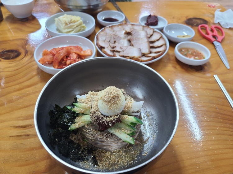 맛있어 보이는 비빔 막국수와 편육, 밑반찬으로 제공된 고추가루로 양념된 무와 백김치
