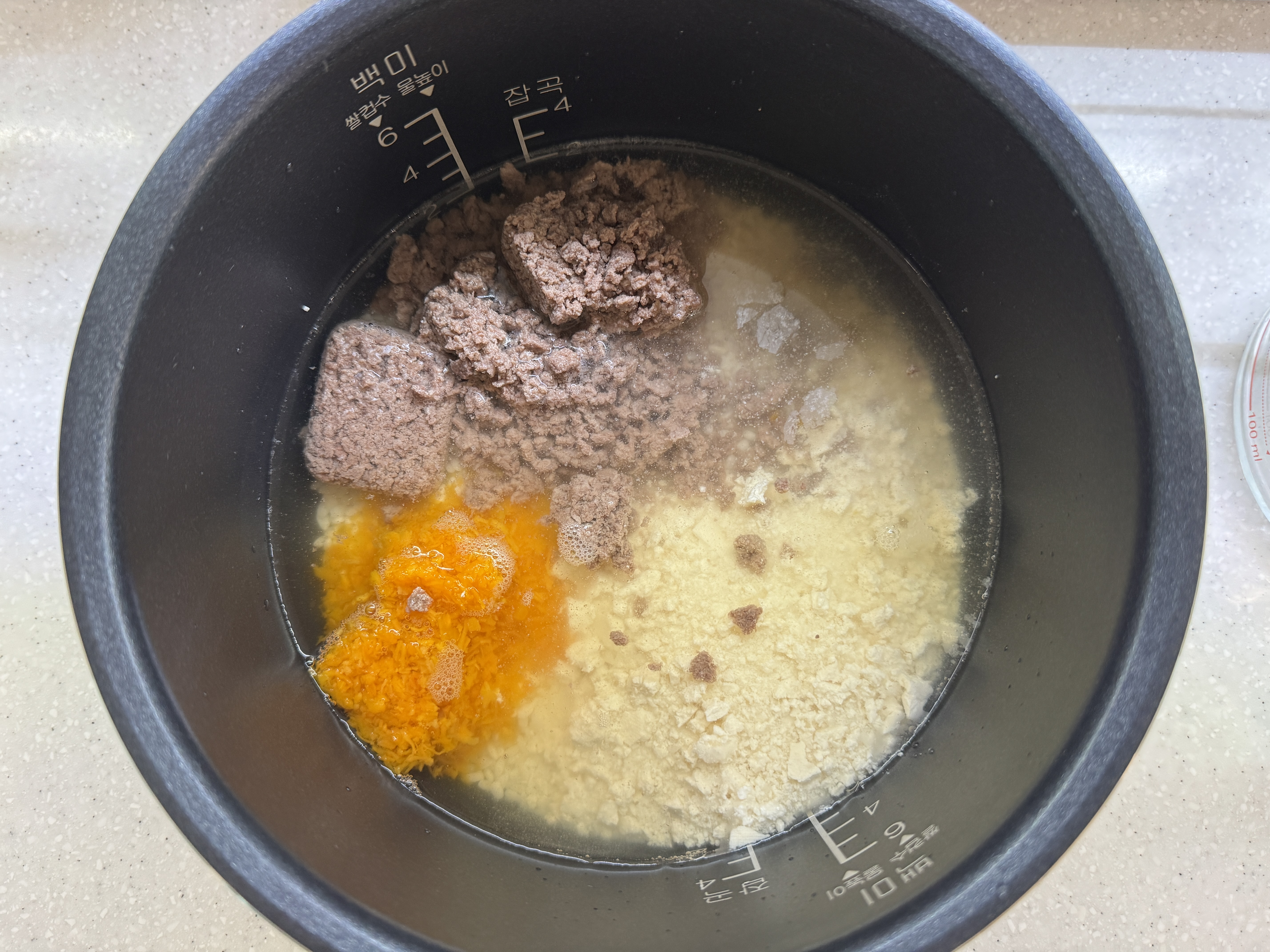 밥솥에 불린 쌀, 채수, 소고기, 단호박, 두부를 넣은 사진