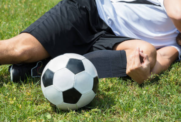 축구 부상으로 다리를 움켜쥐고 있는 선수