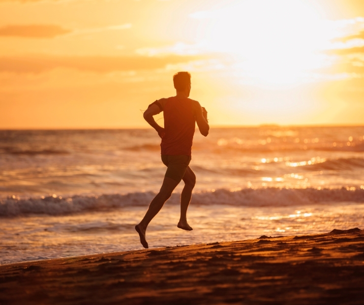 건강한 한 남자가 해질녁에 바닷가를 뛰어가는 모습 via canva