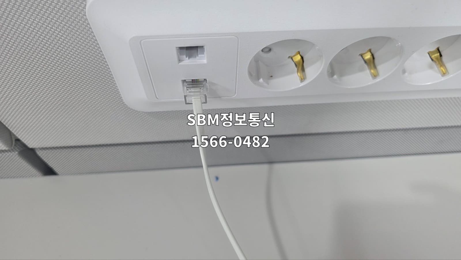업무용 책상 시스템 멀티탭에 내장된 유선 인터넷 포트에 흰색 랜케이블을 다이렉트로 연결한 상태.