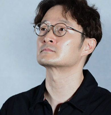 안경을 쓰고 한 쪽을 바라보는 박훈정