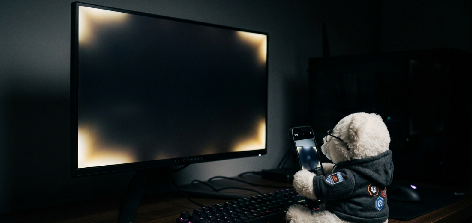 A smartphone taking a photo of white light bleed from the corners of a black monitor