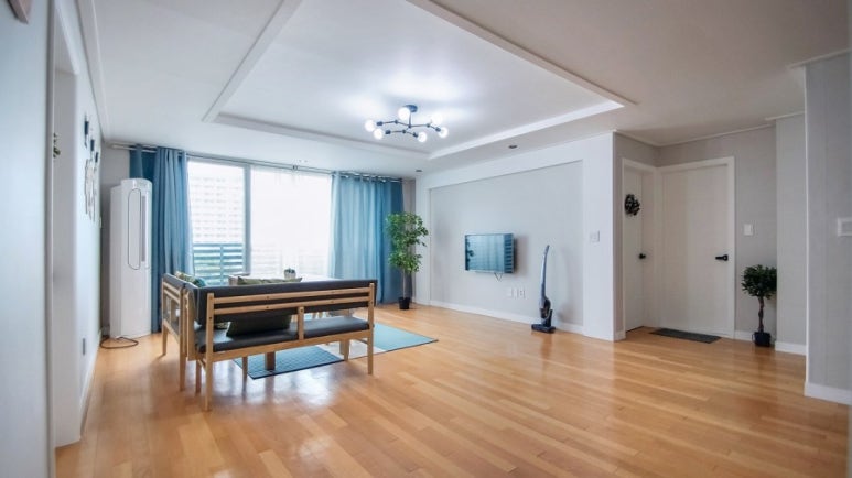 45평형 대형 아파트 쉐어하우스의 넓고 정돈된 거실과 깔끔한 원목 바닥 인테리어