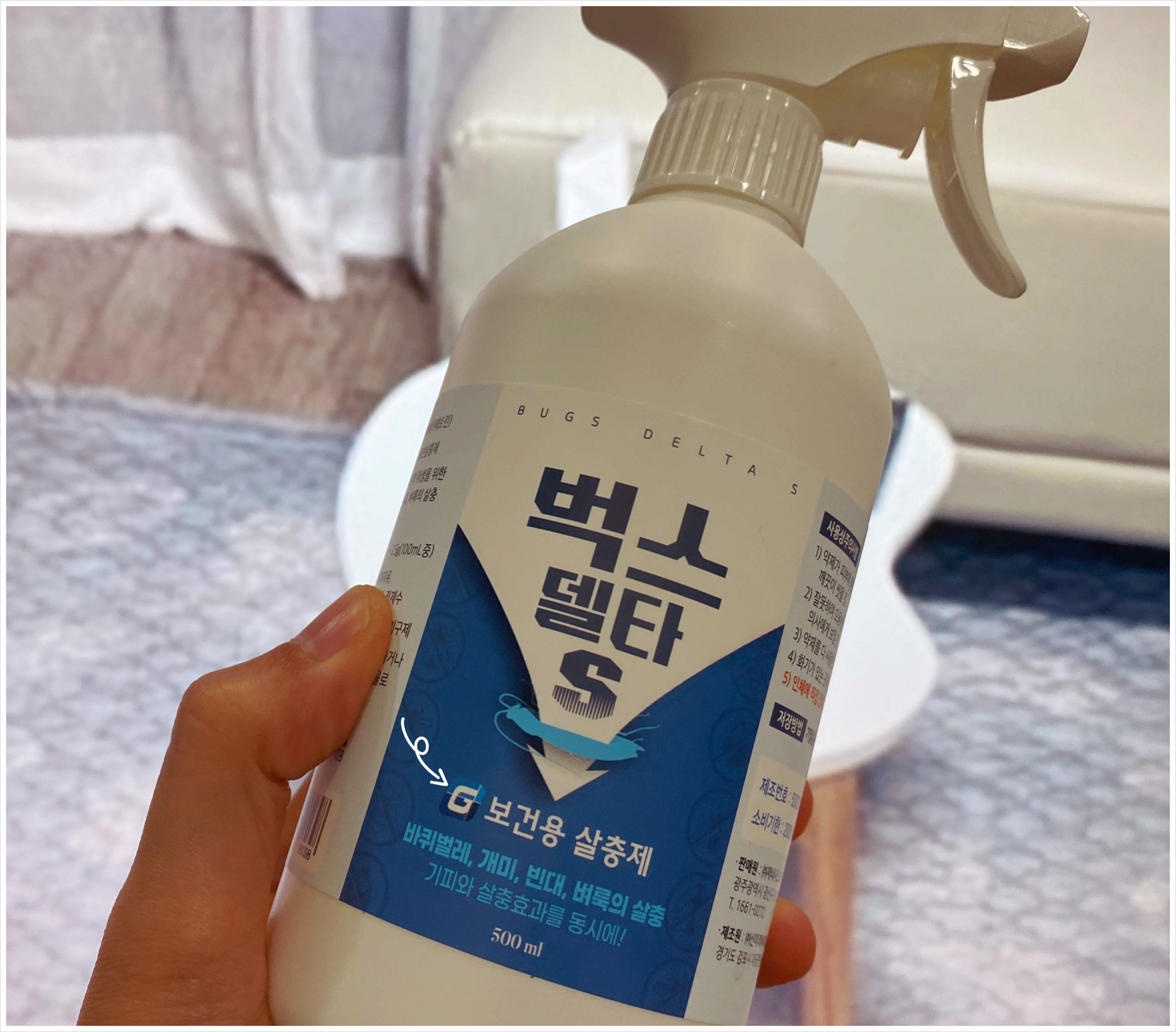사용자의 손에 들려있는 500ml 벅스델타S 보건용 살충제 분무형 용기 전체 모습. 바퀴벌레&amp;#44; 개미&amp;#44; 빈대&amp;#44; 벼룩 퇴치용임을 알리는 파란색 라벨이 부착되어 있다.