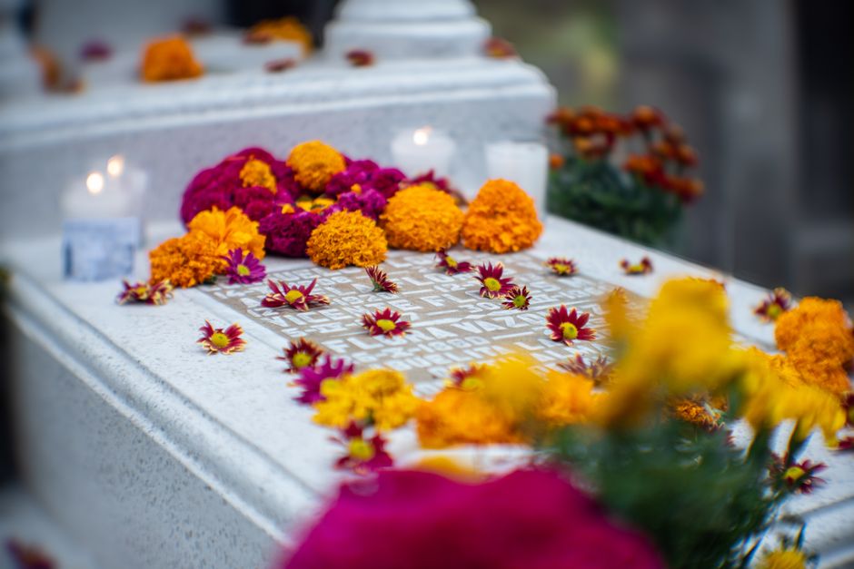 Colorful marigold and chrysanthemum flowers decorate a grave for Dia de Muertos celebration.