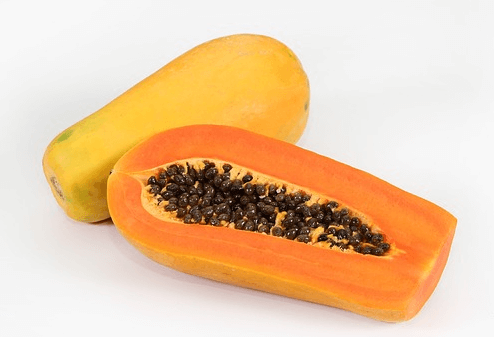 노란 속살에 고동색 씨앗들을 무수히 많이 가진 파파야의 단면과 파파야 한통이 있다.