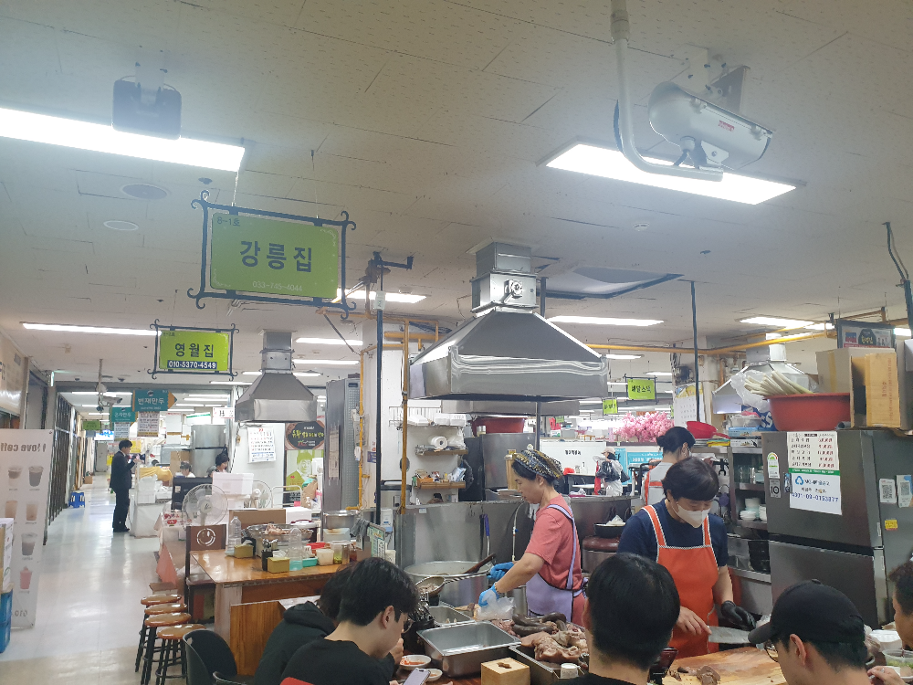 두 명의 직원은 내부에서 일하고 있고 테이블은 손님으로 가득차있다. 옆 가게는 손님이 없다.