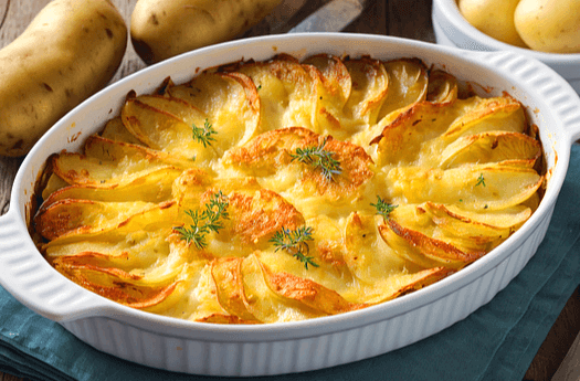 하얀 구이접시에 감자그라탱이 있다. 썰어진 감자들이 익혀져 있고 노란 치즈가 전체를 뒤덮었다.