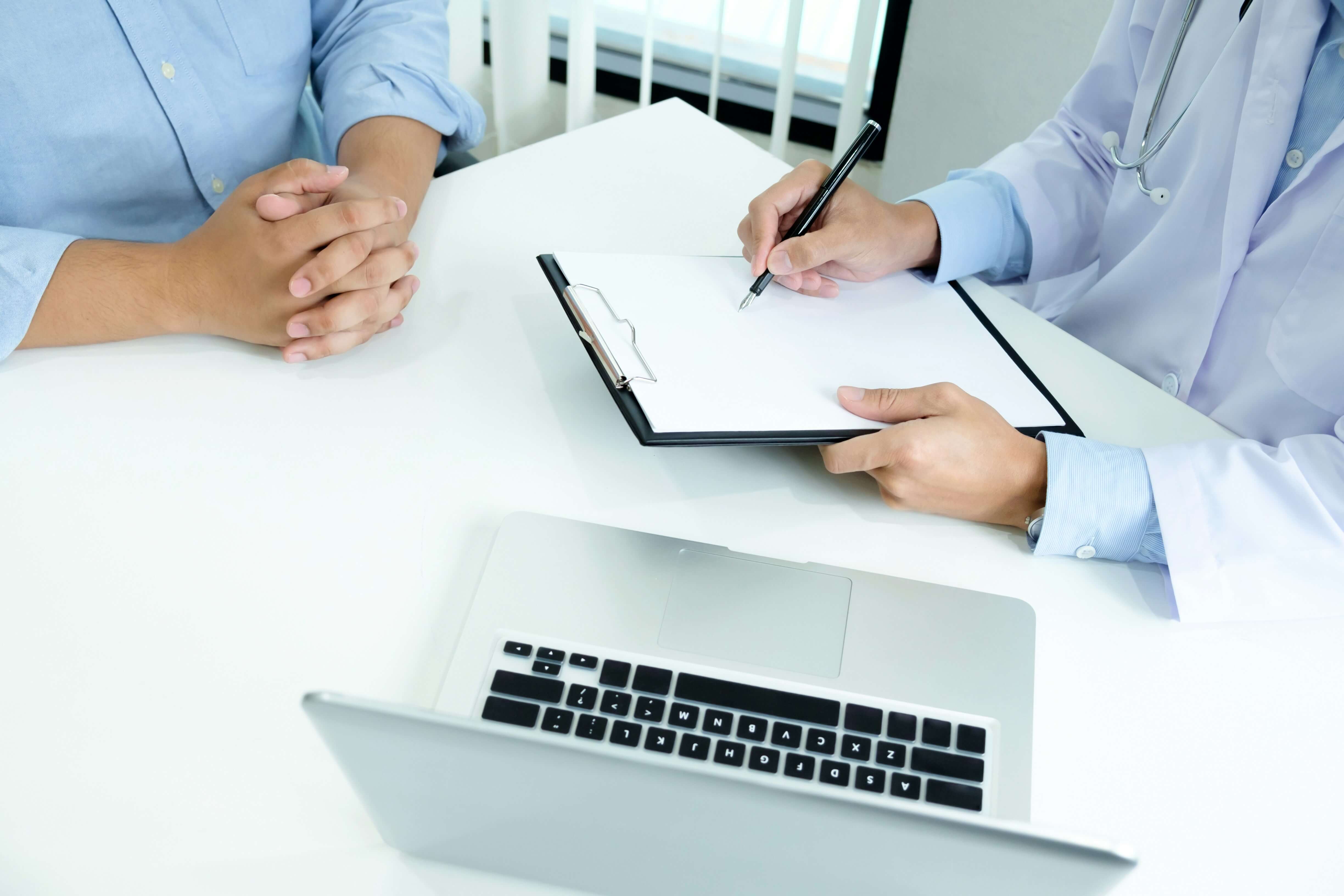의료진이 책상 위 서류에 기재하며 상담 중인 장면