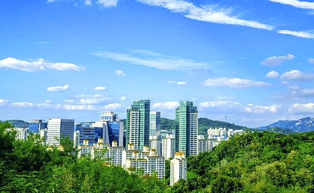 높은 빌딩들이 가득한 서울시내 풍경이다. 파란 하늘과 푸른 나무들이 주변에 가득하다.