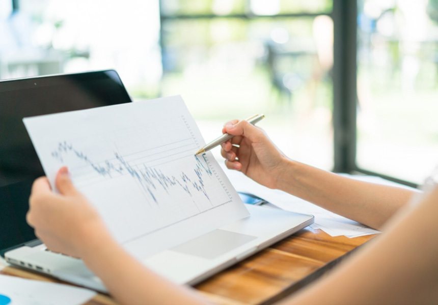 노트북 앞에서 주식 차트를 분석하는 모습, 투자 전략을 상징하는 그래프