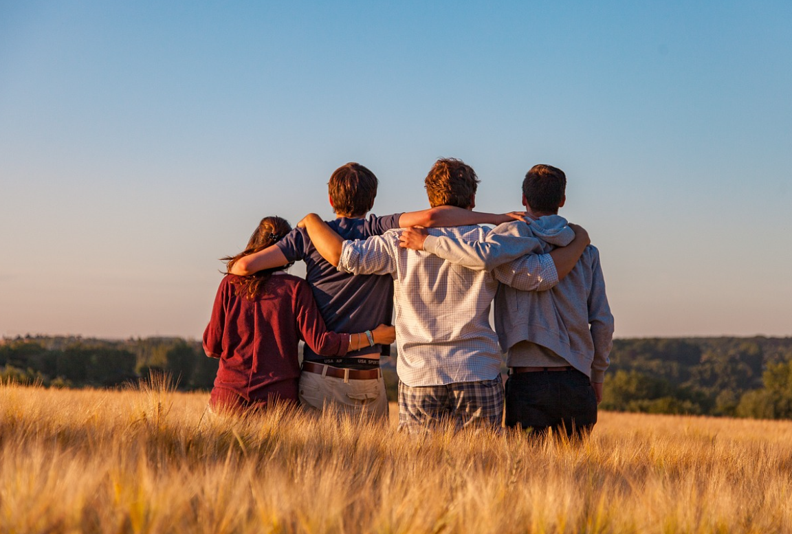 어깨동무하고 들판에 앉아있는 네 친구