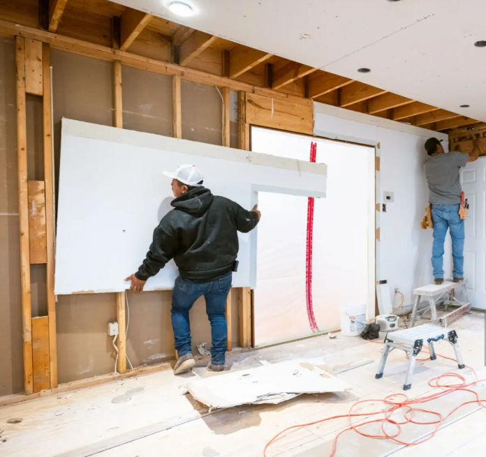 two men putting up drywall