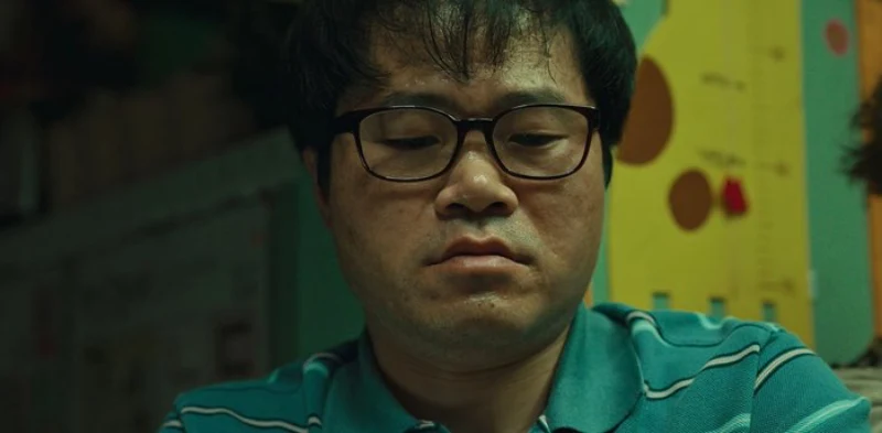 청녹색 티셔츠에 검은 뿔테 안경을 쓰고 있는 스위트홈 시즌2에서 강승완을 맡은 배우 우정국