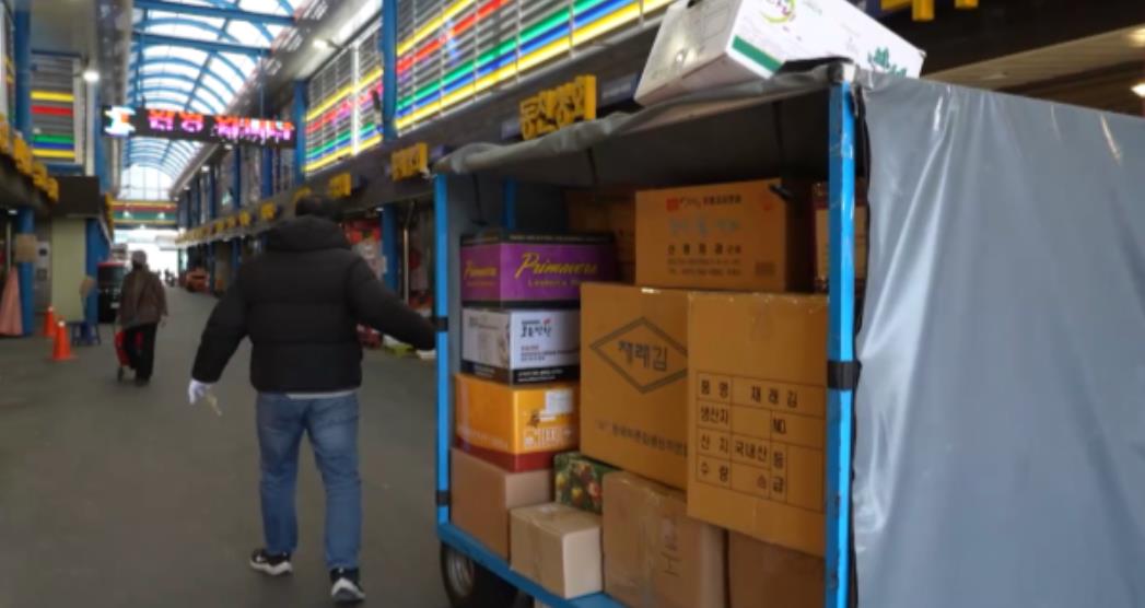 극한직업 시장배달서비스로 시장에서 구매한 물건을 옮기는 모습